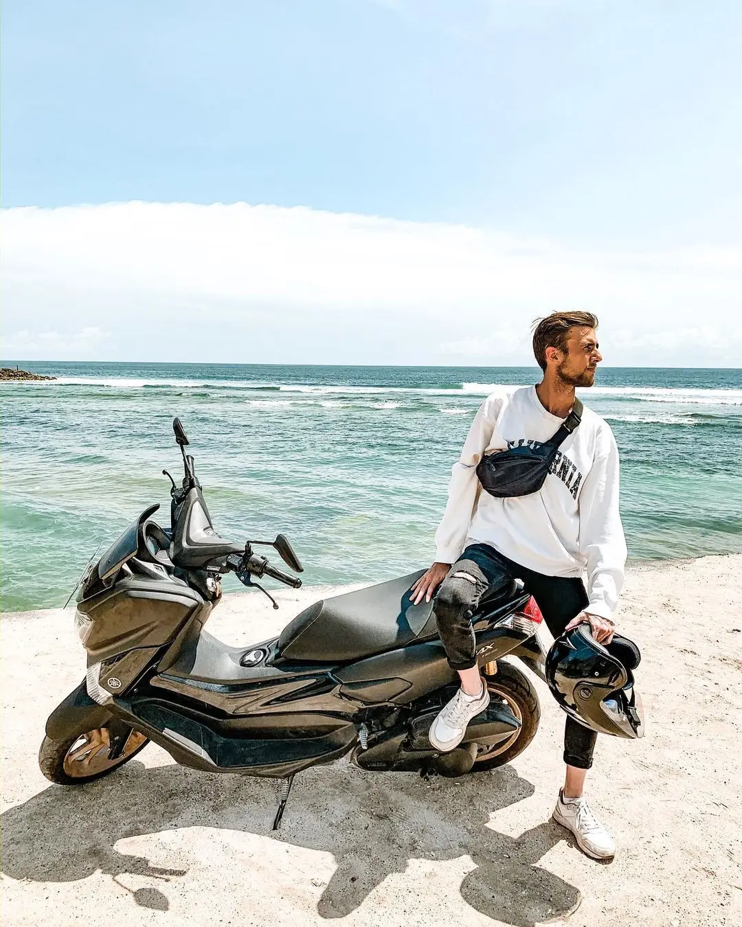 Roman sitting on a scooter near the ocean